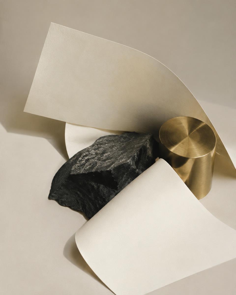 Still life of ivory paper, dark stone and brass exploring a visual direction